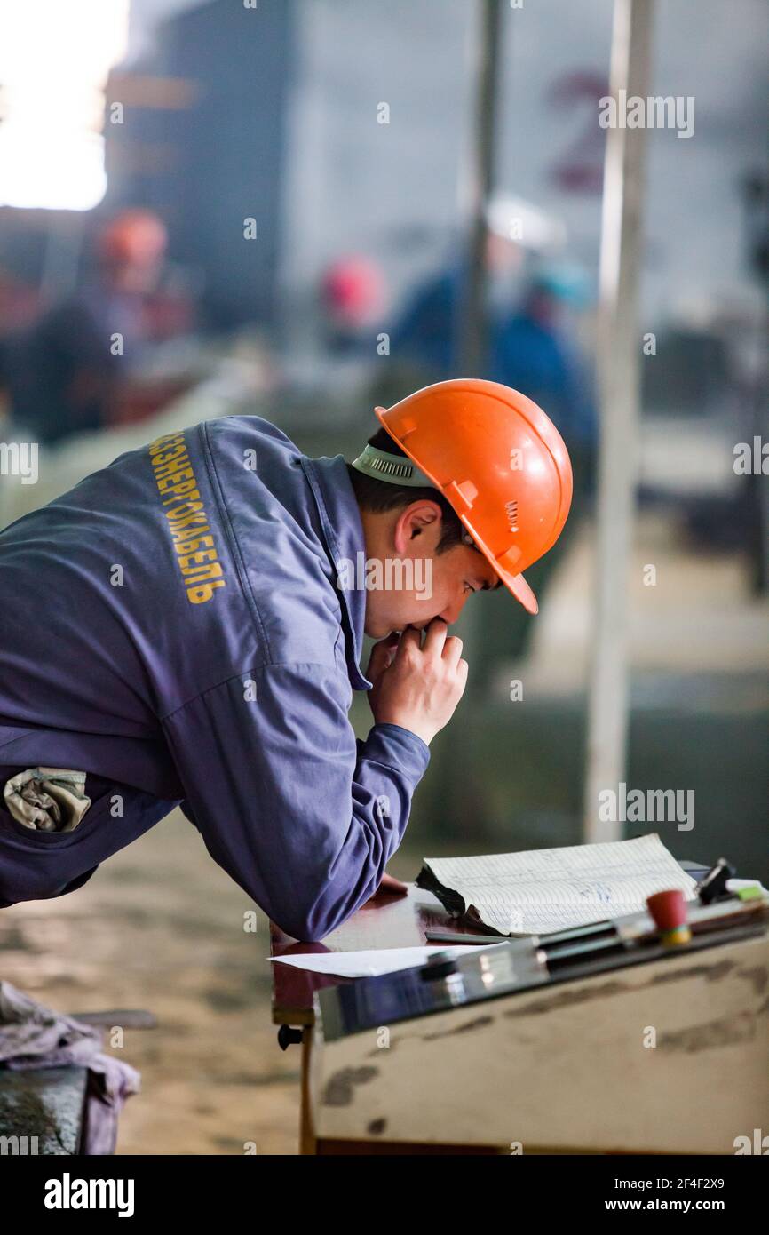 Pavlodar, Kasachstan - Mai 29 2012: Aluminium-Draht-und Kabel-Anlage. Betreiber Arbeiter in orange Hardhat lesen Sie ein Logbuch. Stockfoto