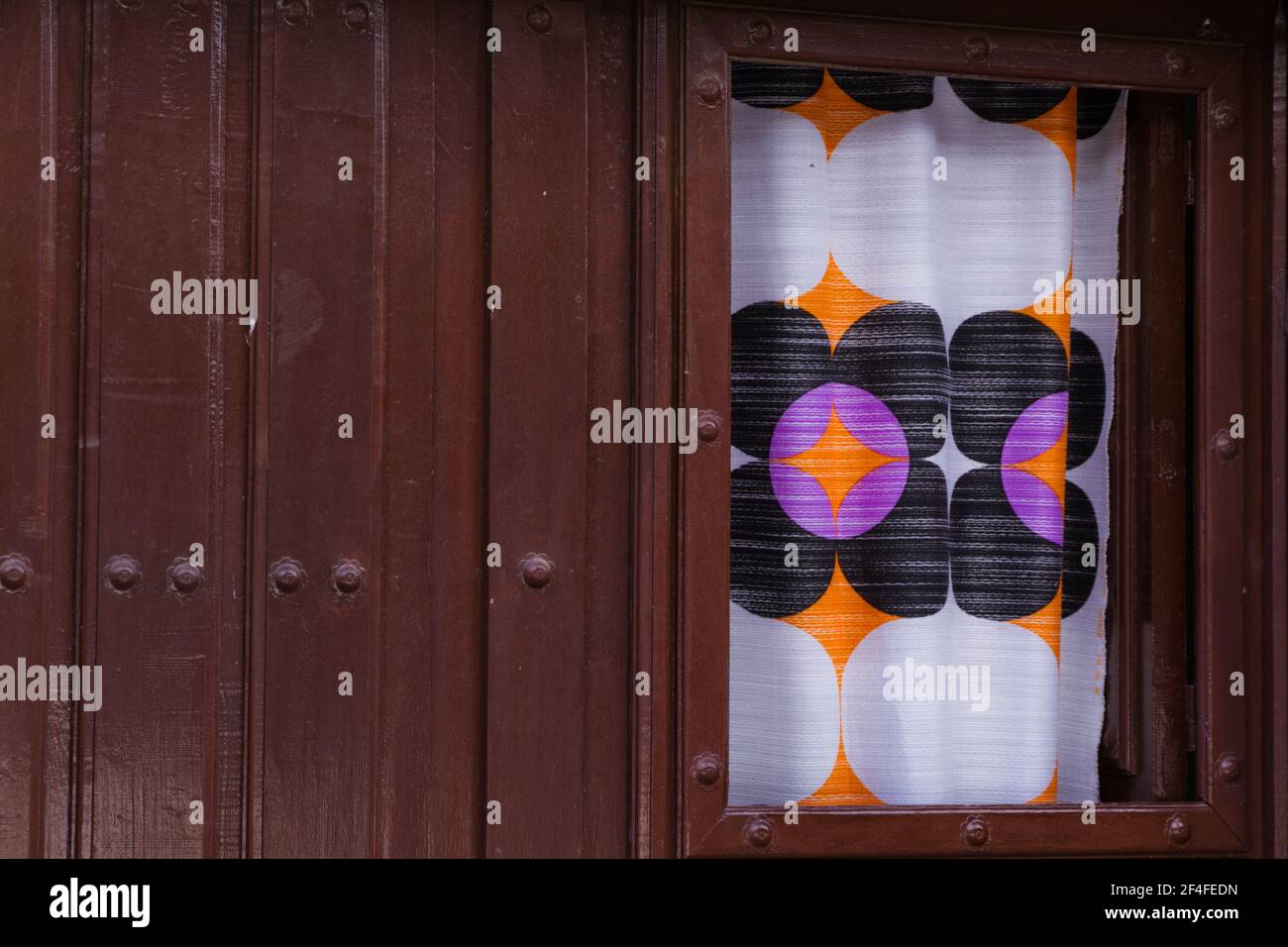 Alte Holztür mit EINEM Fenster von EINEM bunten bedeckt Vorhang Stockfoto