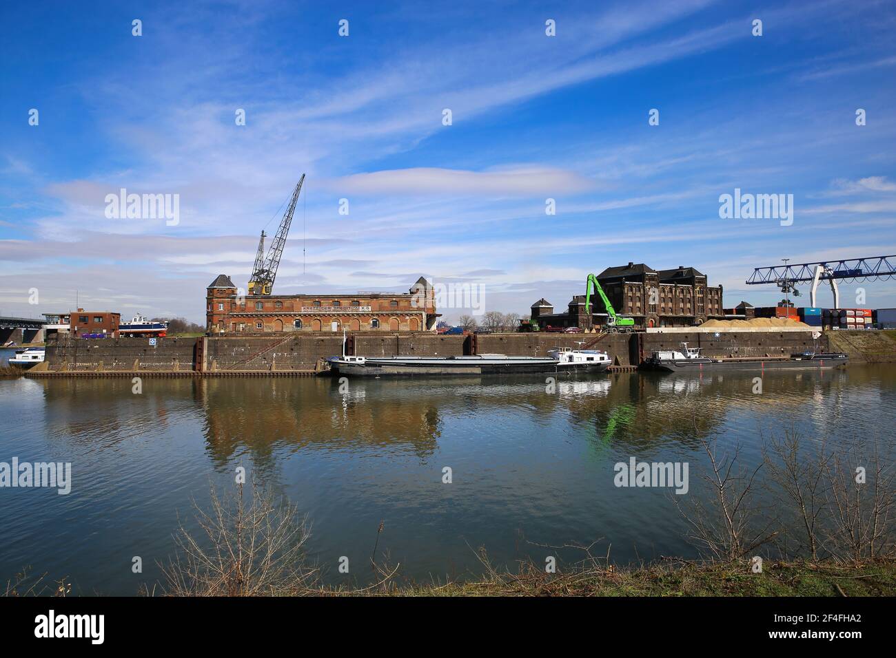 Krefeld (Ürdingen) - März 1. 2021: Blick auf alten Binnenladerhafen am Rhein mit Kran, Wasserschiff und Fabrikgebäude gegen Blue sk Stockfoto