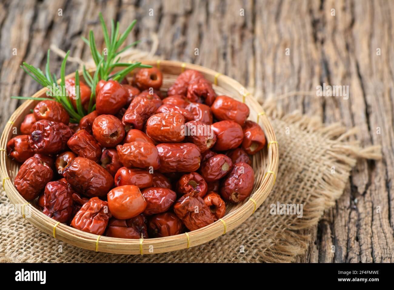 Getrocknete Jujube, chinesische getrocknete rote Dattobst in Bambuskorb auf altem Holzhintergrund, Kräuterfrüchte. Es hat mehr Vitamin C, die Kampf frei radica hilft Stockfoto