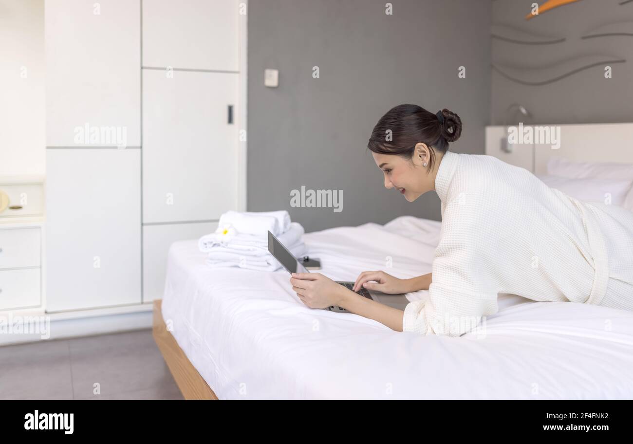 Junge hübsche Frau arbeitet mit Laptop auf dem Bett, Nachrichten beobachten, für Prüfungen lesen, Social Network Chat, Internet-Surfen Konzept Stockfoto