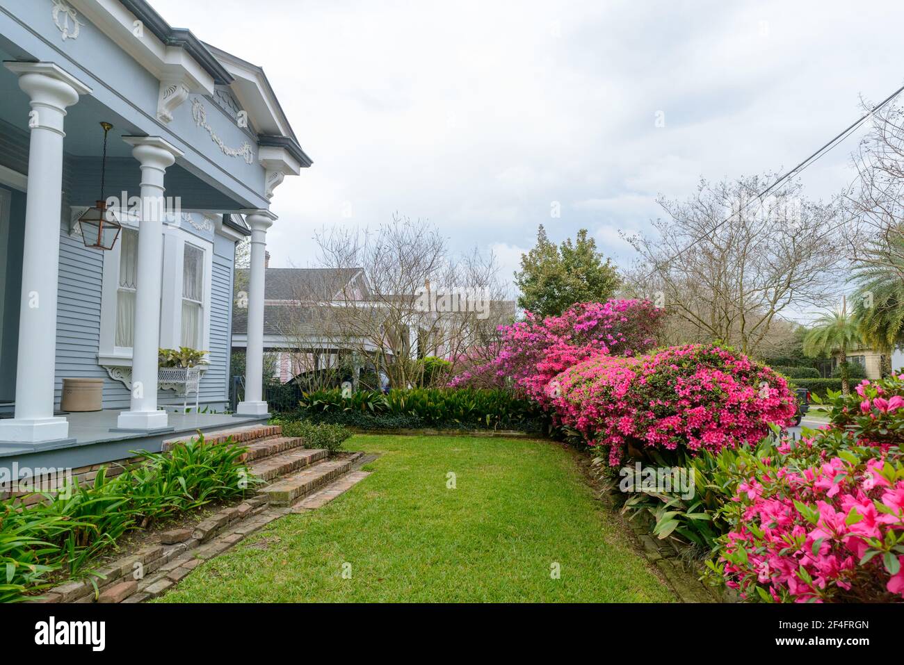 Haus und Vorhof im Kolonialstil aus den 1890er Jahren mit Rasen und blühenden Azaleen in Uptown New Orleans Stockfoto