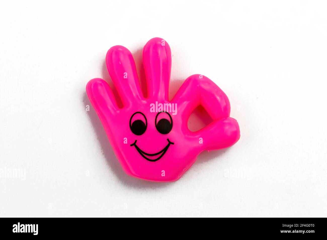 Kleine fuchsia rosa Plastikhand mit Smiley Gesicht macht das OK-Zeichen! Isoliert auf weißem Hintergrund Stockfoto