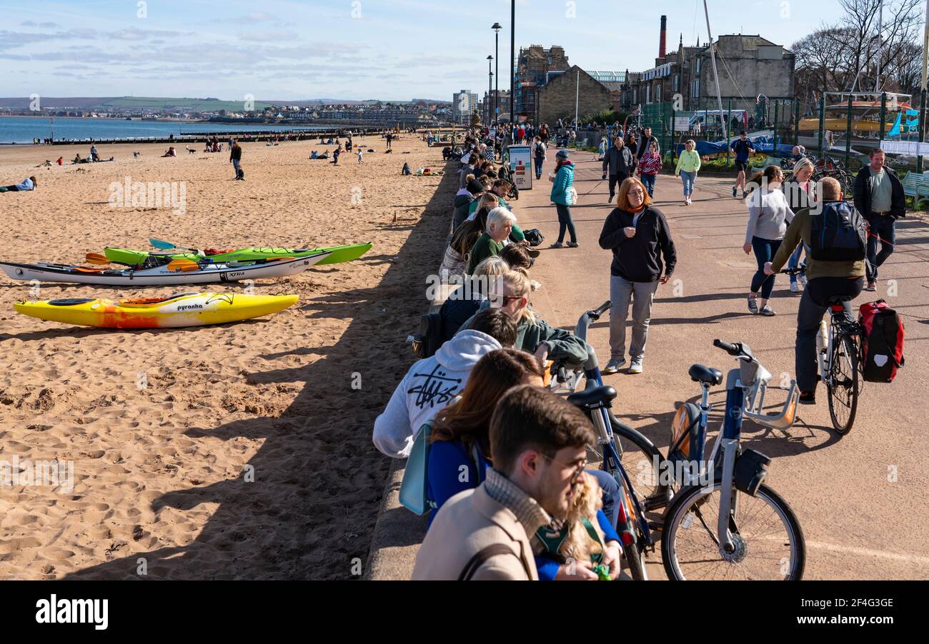 Portobello, Schottland, Großbritannien. 21. März 2021. Warme Temperaturen, blauer Himmel und Sonnenschein brachten die Massen an diesem Nachmittag zum beliebten Portobello Strand und zur Promenade. Trotz der andauernden covid-19 Lockdown wurde die Küste mit Mitgliedern der Öffentlichkeit gedrängt. Viele Cafés waren offen und boten Essen zum Mitnehmen an. Iain Masterton/Alamy Live News Stockfoto
