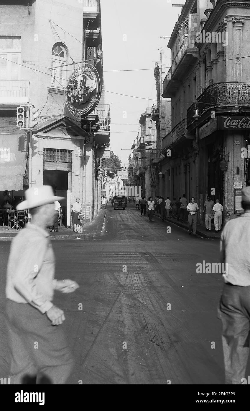 Langaufnahme einer Feldkreuzung, mit Fußgängern, Gebäuden aus der Kolonialzeit und ein paar Autos in der Ferne, in der Innenstadt (Stadtzentrum) Havanna, Kuba, 1964. Aus der Sammlung Deena Stryker Photographs. () Stockfoto