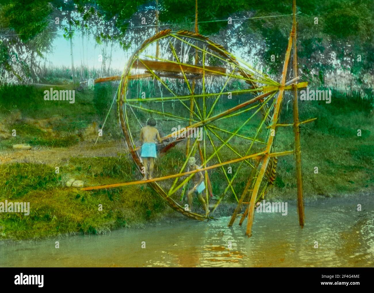 Wide-shot von zwei Männern, manuell mit einem großen hölzernen Wasserrad, um ihre Felder zu bewässern, Sichuan, China, 1917. Aus der Sammlung Sidney D. Gamble Photographs. () Stockfoto