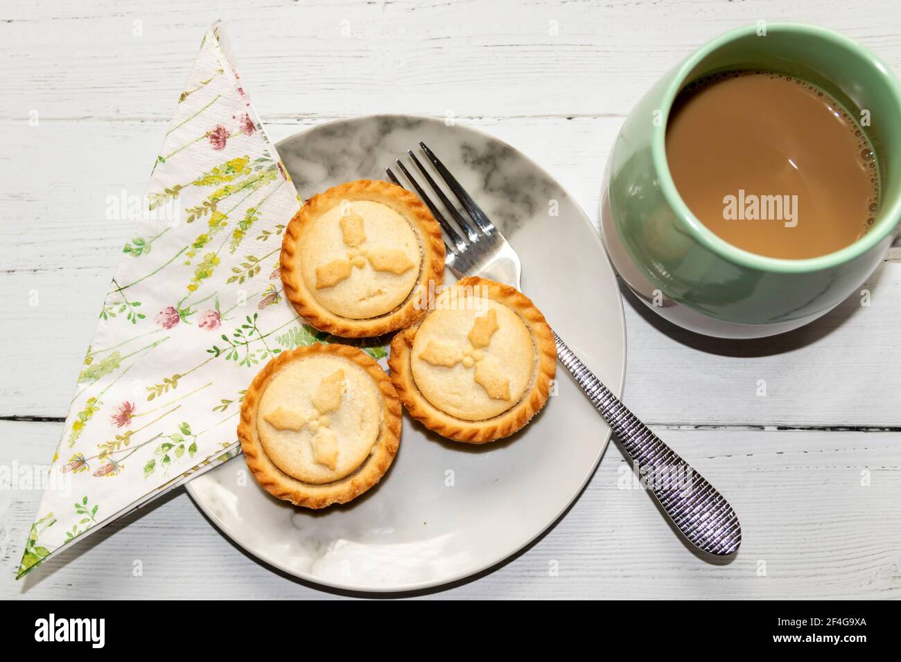 Mince Pies auf einem Beilagenteller mit einer Tasse Kaffee zur Seite Stockfoto