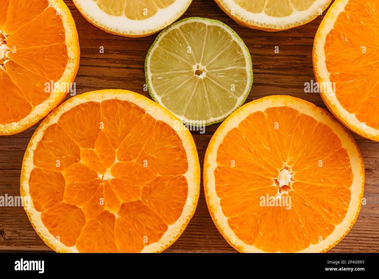 Orangen, Limetten und Zitronen Rutschen auf Holztisch Blick von oben. Wunderschön Hintergrund mit frischem Obst halb geschnitten.gesunde Ernährung Vitamin C.Sommer tropica Stockfoto