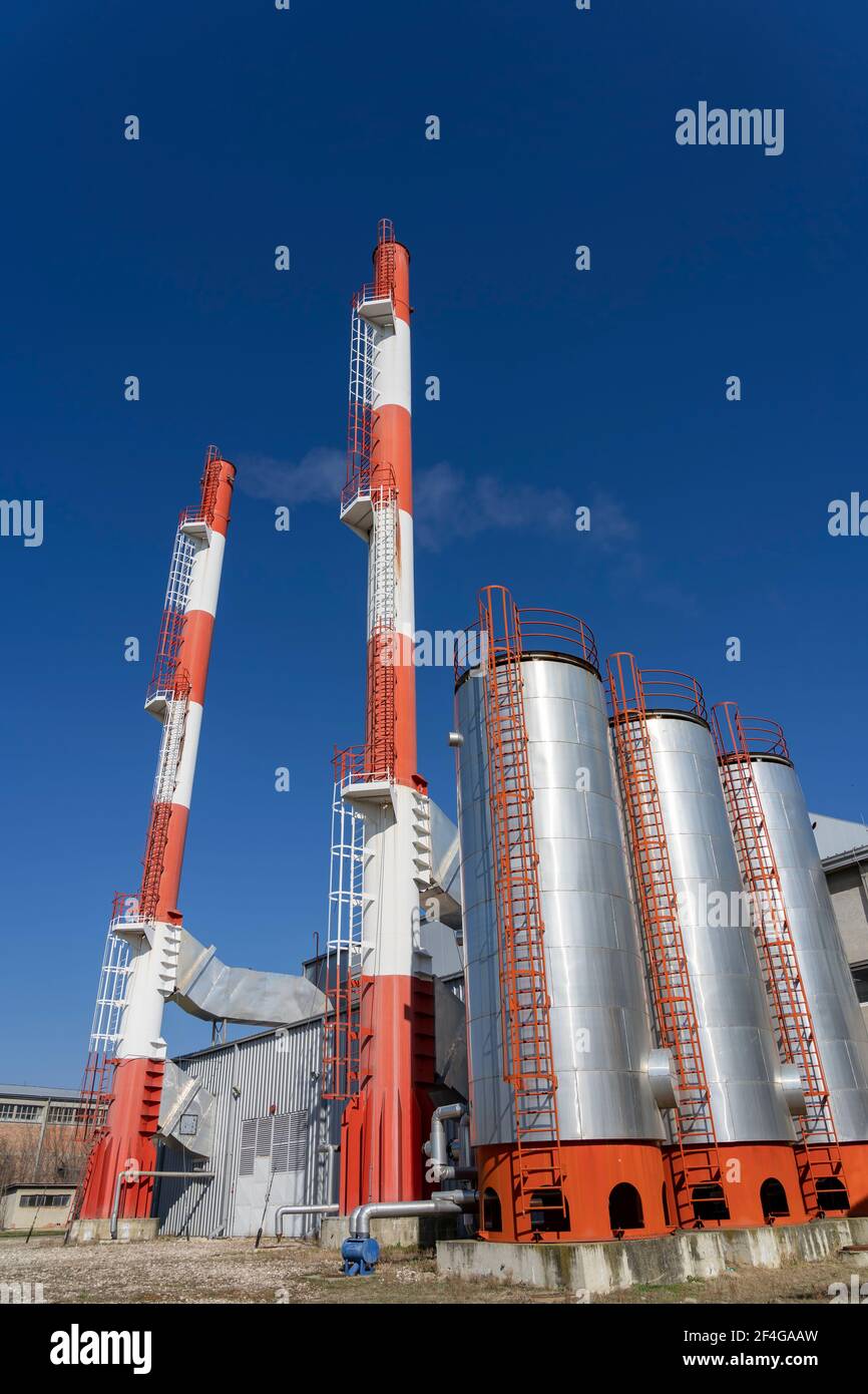 Außenansicht der Fernwärmeanlage mit Industriekaminen gegen den blauen Himmel. Rauch aus den Schornsteinen des Industriekraftwerks. Low-Angle-Ansicht. Stockfoto