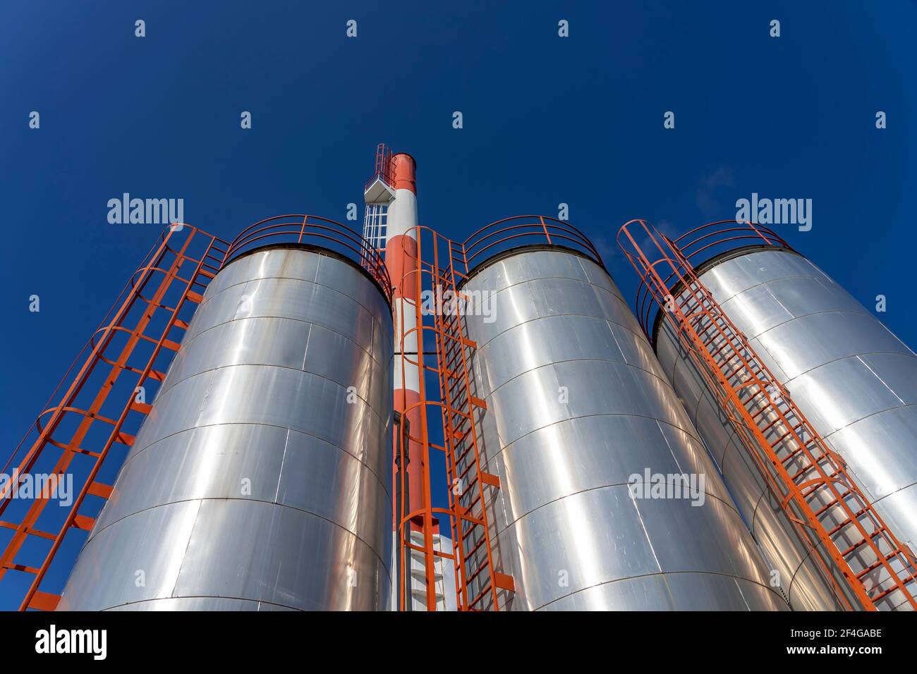 Industrielle Lagertanks Über Blue Sky Hintergrund. Außenansicht der Ölraffinerie mit Öllagertanks und Industriekamin gegen den blauen Himmel. Stockfoto