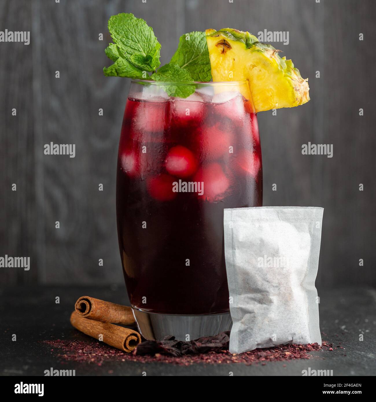 Eisgekühlter Zobo-Tee in einem hohen Glas, auf einem Schieferhintergrund, umgeben von den Zutaten des Getränks Stockfoto