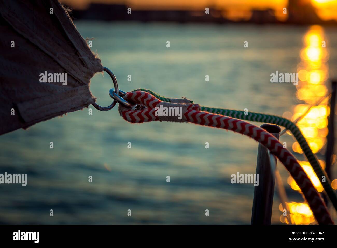 Detail der Befestigung des Segels auf einer Yacht in den Strahlen des Sonnenuntergangs. Schießen an Bord einer Yacht auf dem Fluss. Stockfoto