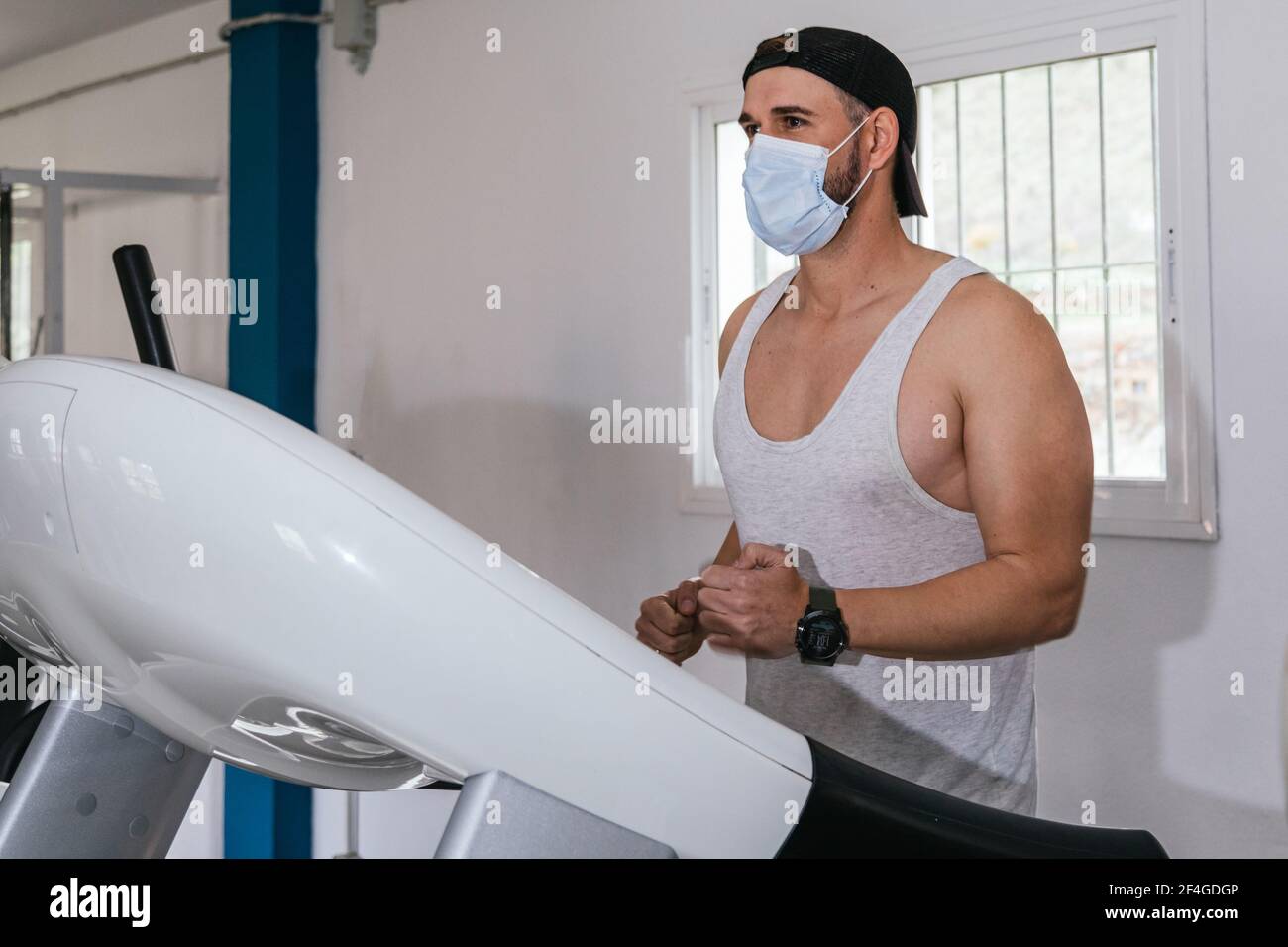 Mann, der auf einem Laufband läuft und eine Maske trägt. Covid19. Gesundheits- und Sicherheitskonzept. Stockfoto