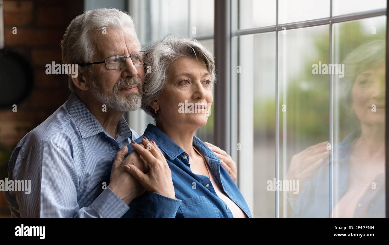 Ältere Ehepartner umarmen Blick auf Fenster treffen Dämmerung Jahre zusammen Stockfoto