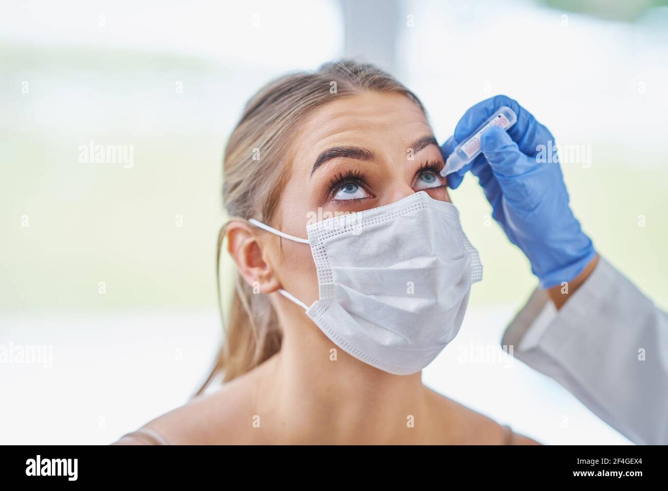 Auge-Arzt in Maske Überprüfung auf weibliche Patientin Stockfoto