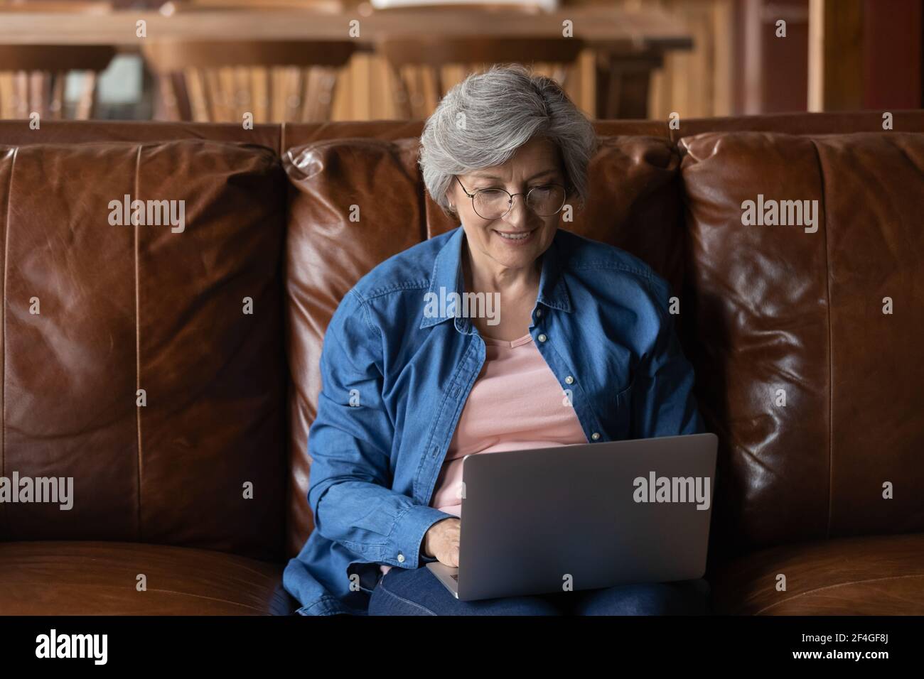 Ältere lateinische Dame sitzen auf dem Sofa Laptop auf den Knien halten Stockfoto