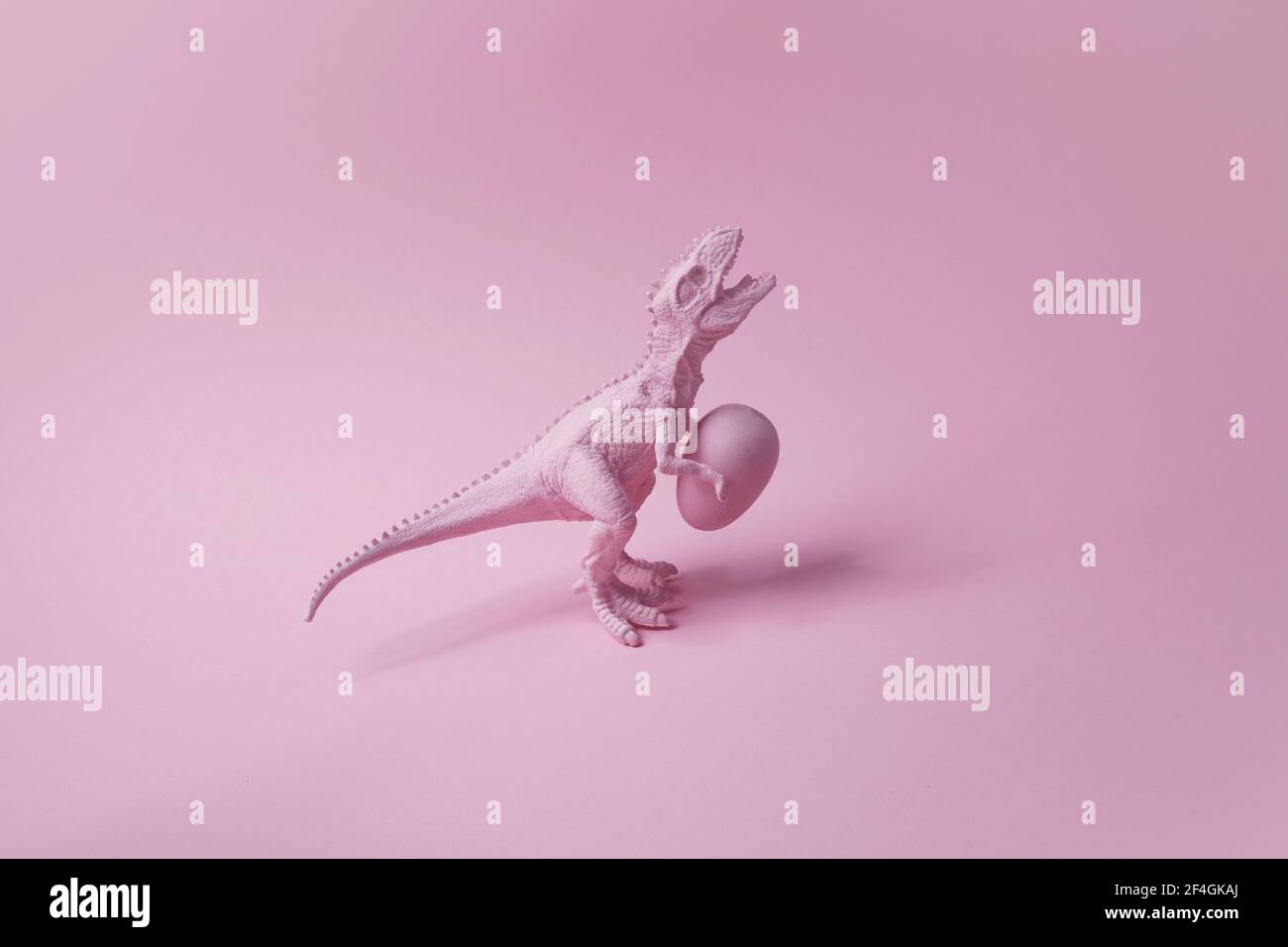 T rex Dinosaurier mit osterei auf rosa Hintergrund. Lustige Ester grüssen. Stockfoto