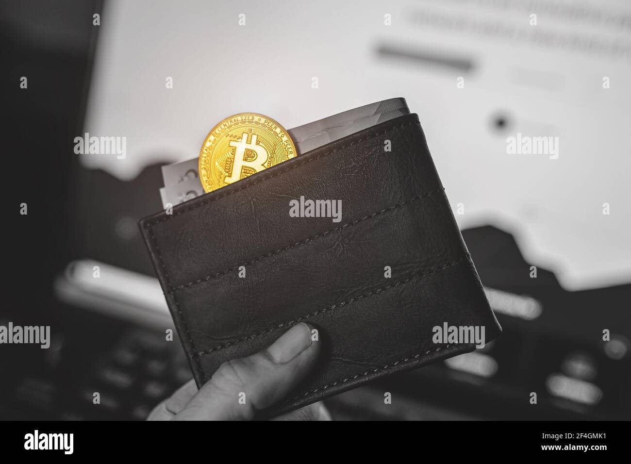 Mann hält Gold Bitcoin in Brieftasche mit britischen Pfund Bargeld, verschwommen Website Hintergrund. Schwarz und Weiß außer Gelb, selektive Farbe Stockfoto