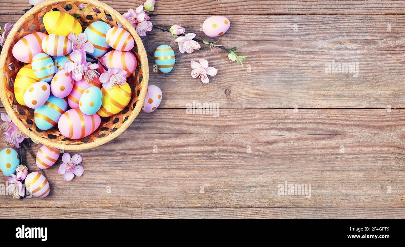 Frohe Ostern Hintergrund mit rosa; gelb, blaue Eier und schöne Frühlingsblumen auf Holztisch. Geschenkkarte mit bunten ostereiern auf alten Holzt Stockfoto
