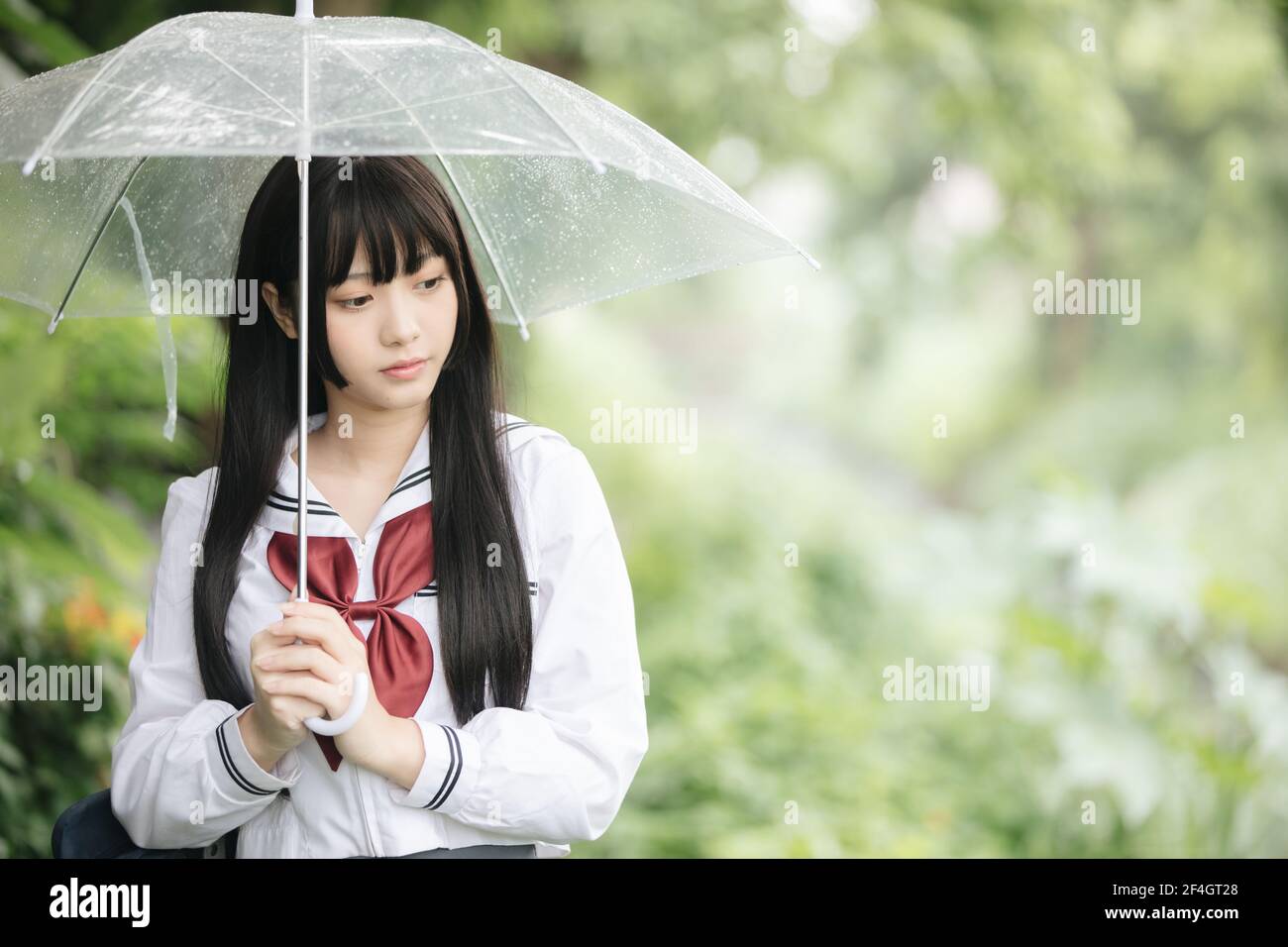 Portrait von asiatischen Schule Mädchen gehen mit Regenschirm auf die Natur Gehweg auf Regen Stockfoto