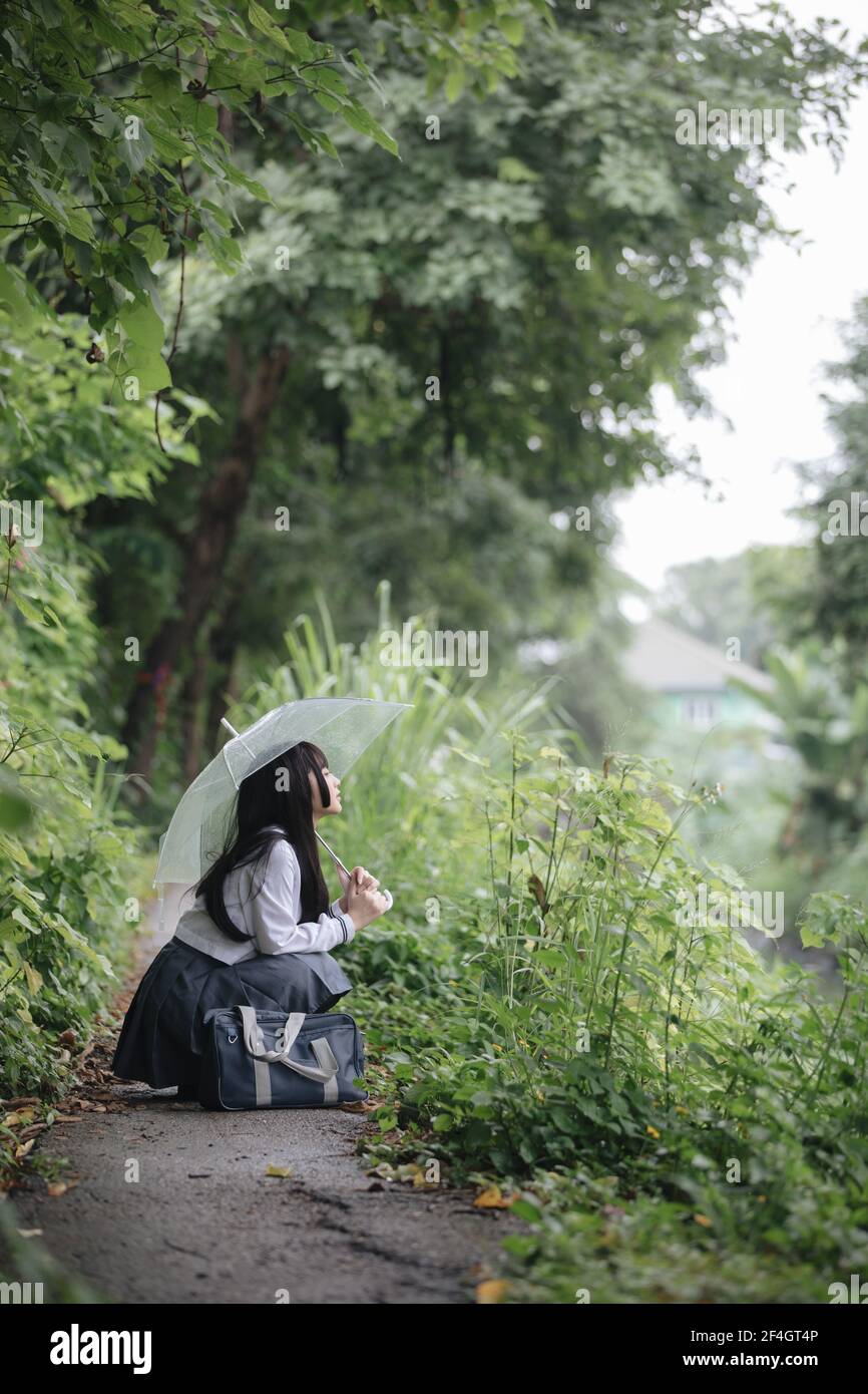 Portrait von asiatischen Schule Mädchen gehen mit Regenschirm auf die Natur Gehweg auf Regen Stockfoto