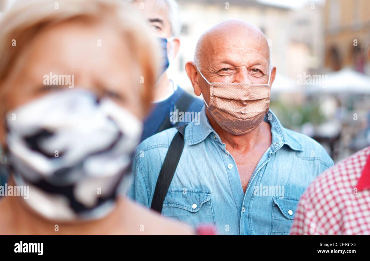 Menschenmenge, die mit Gesicht die Straßen der Stadt entlang geht Maske ein - Kamera fokussiert einen alten Mann - Neu Lifestyle Stockfoto