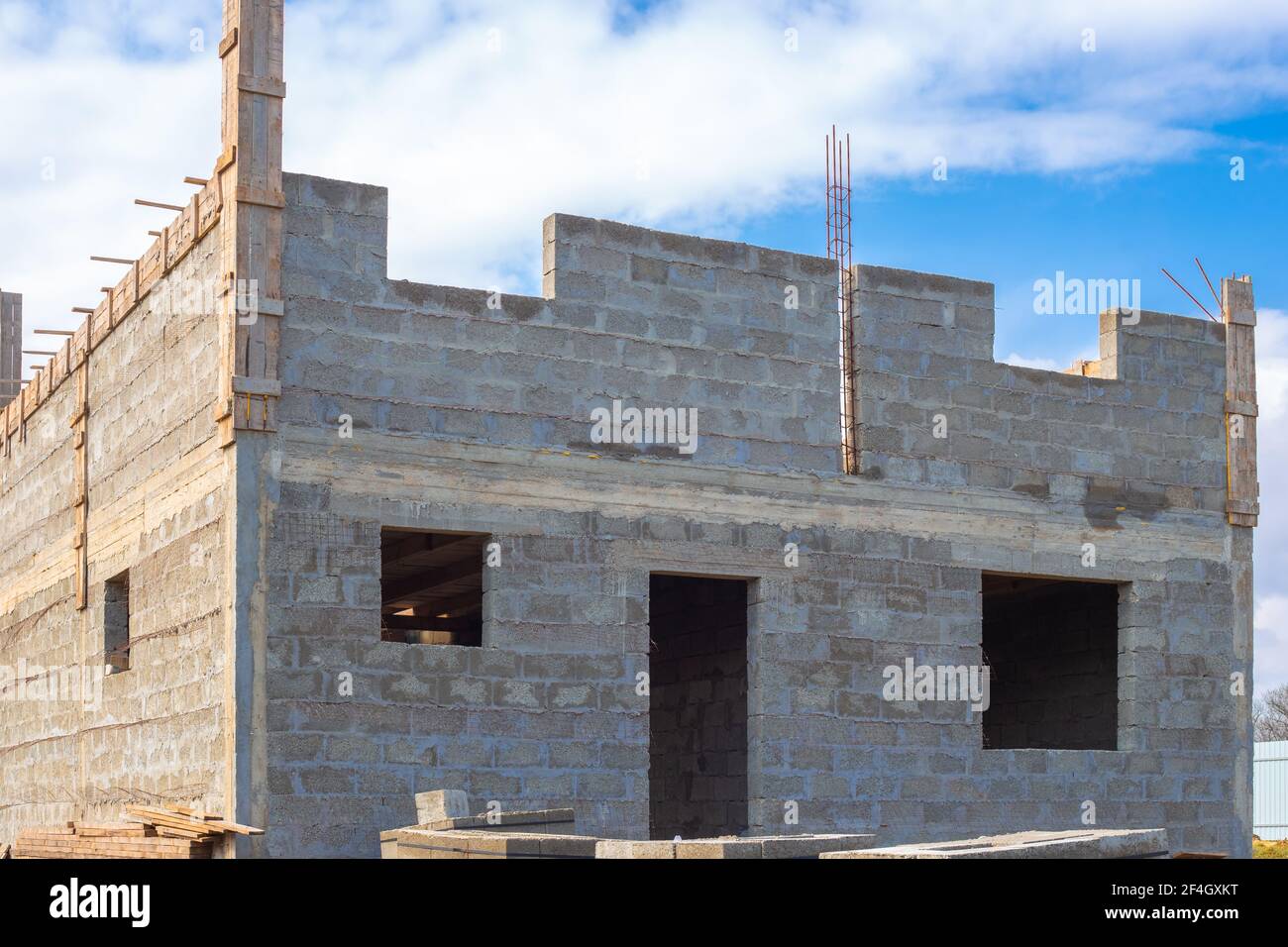 Bau von Gebäuden aus Zinder Block. Baustelle eines zweistöckigen Landhauses aus grauen großen Ziegelblöcken mit hervorstehender Fittine Stockfoto