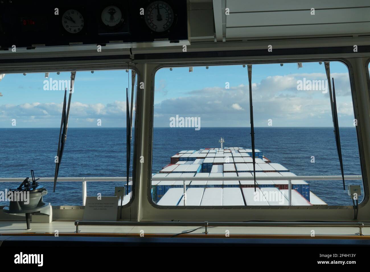 Blick aus dem Fenster der Navigationsbrücke des Containerschiffes auf die mit Schnee bedeckten Container unterwegs durch den Pazifischen Ozean. Stockfoto