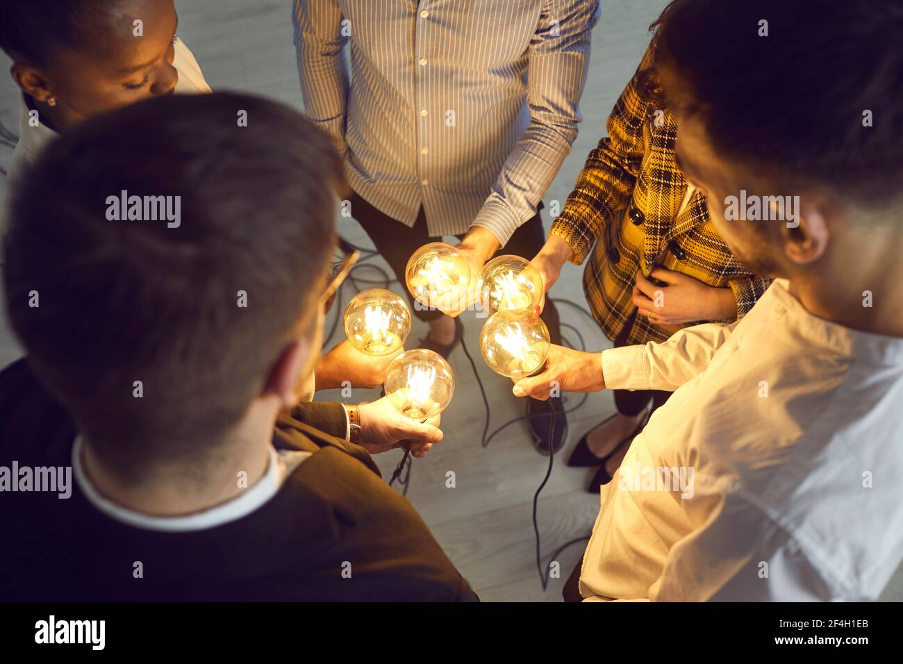 Konzeptionelle Aufnahme verschiedener Geschäftsleute mit Glühbirnen Im Kreis stehend Stockfoto
