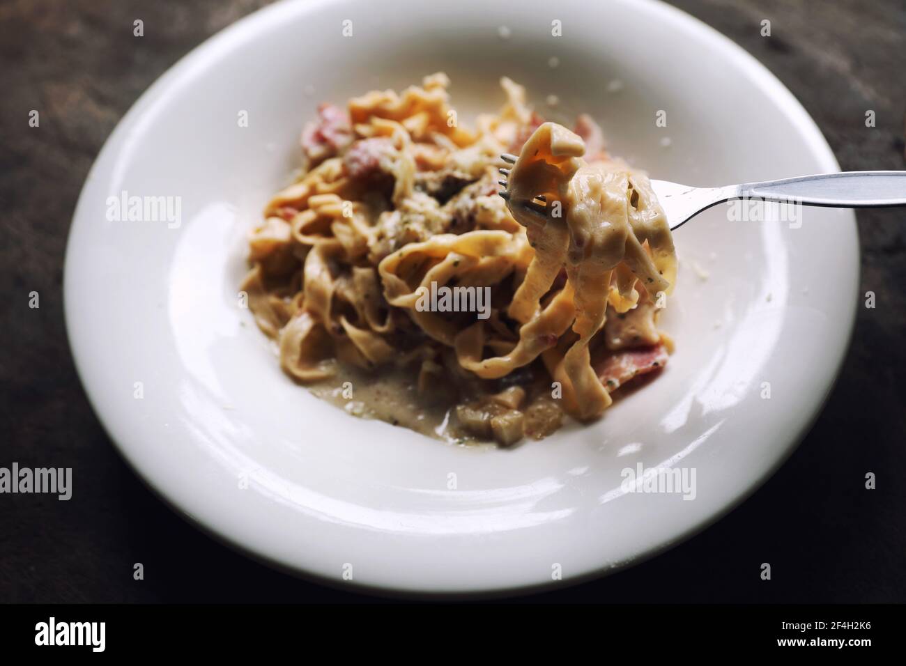 Pasta weiße Sauce mit Speck und Pilz auf Holz Hintergrund In mystischem Licht Stockfoto