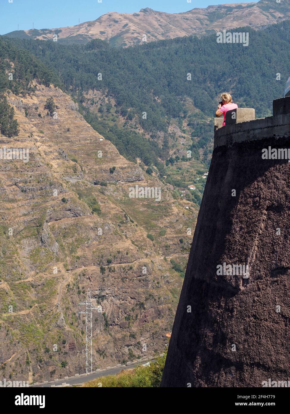 Madeira, Portugal. 09,05,2017 Frau, die von einem steinernen Aussichtspunkt aus über ein großes Tal zwischen den Bergen der Insel Madeira blickt. Stockfoto