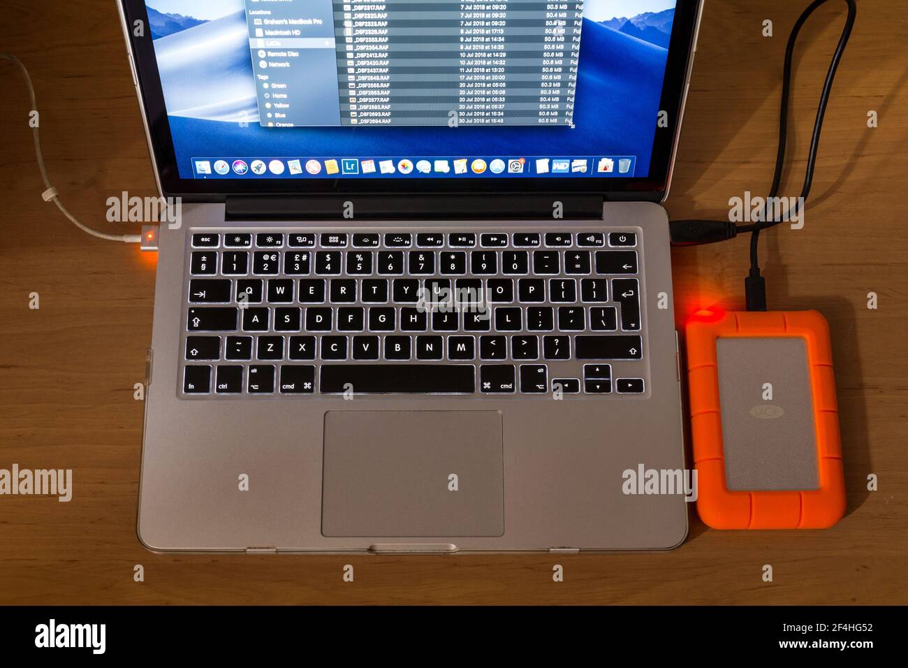 Laptop-Computer mit einer robusten externen LaCie-Festplatte.Sichern von Daten. Stockfoto