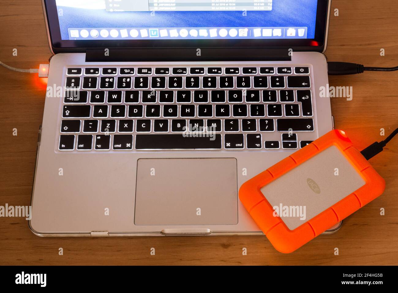 Laptop computer with a LACie rugged external hard drive attached. Backing up data. Stockfoto
