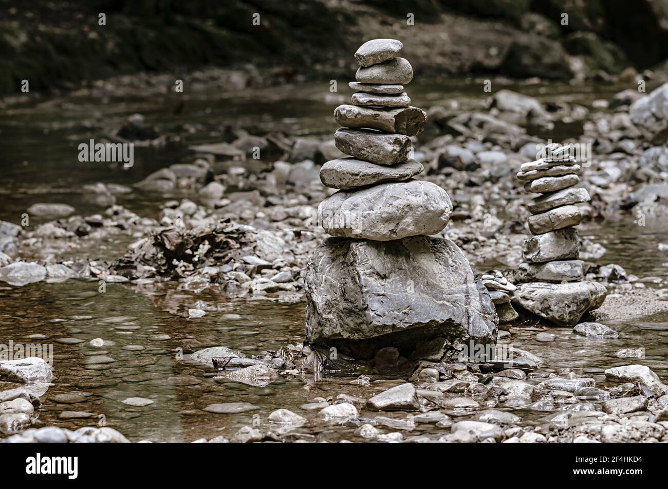 Zwei Stapel von gestapelten Felsen, balanciert in einem Flussbett. Felsen lagen flach aufeinander zu großer Höhe. Balancierte Gesteinshaufen am Bach. Stockfoto