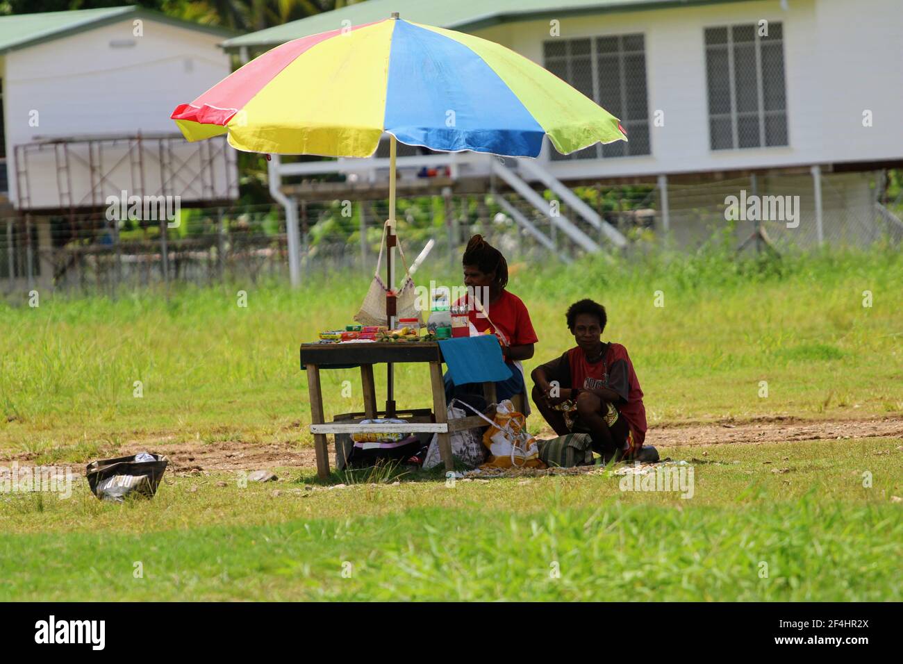 Frauen auf dem informellen Markt verkaufen ihre Waren auf einem provisorischen Tisch unter einem Sonnenschirm vor dem Flughafen Madang. Stockfoto