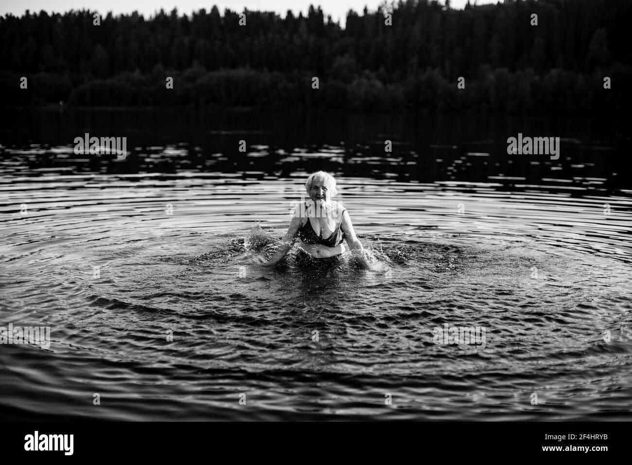 Alte Frau schwimmt im Sommer im Fluss. Schwarzweiß-Foto. Stockfoto