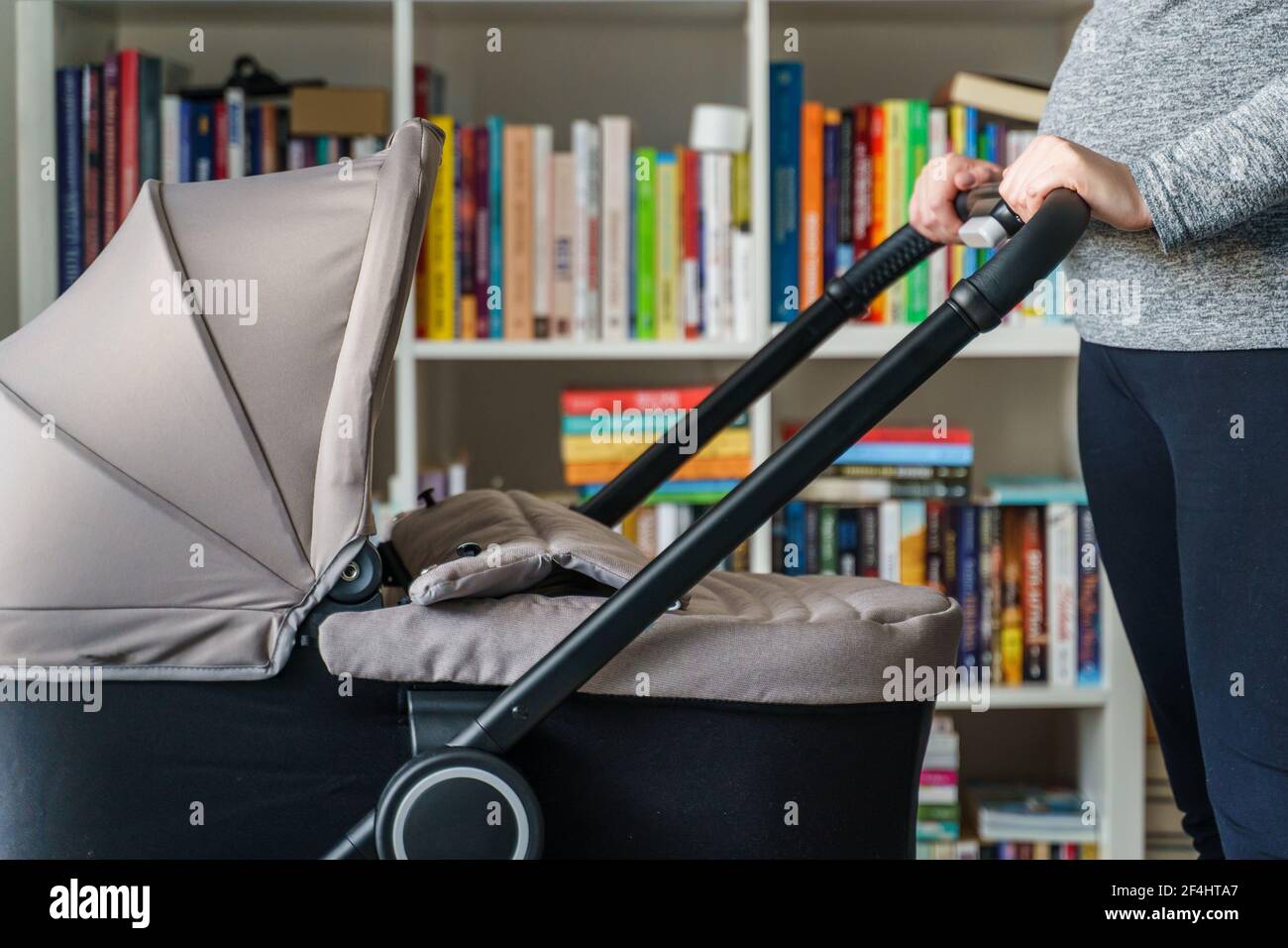 Nahaufnahme des Mittelabschnittes einer unbekannten schwangeren Frau aus Kaukasien in der Hand Ihr Bauch beim Überprüfen der Babykutsche - Mutterschaft und Schwangerschaft Mit Kinderwagen Eiter Stockfoto