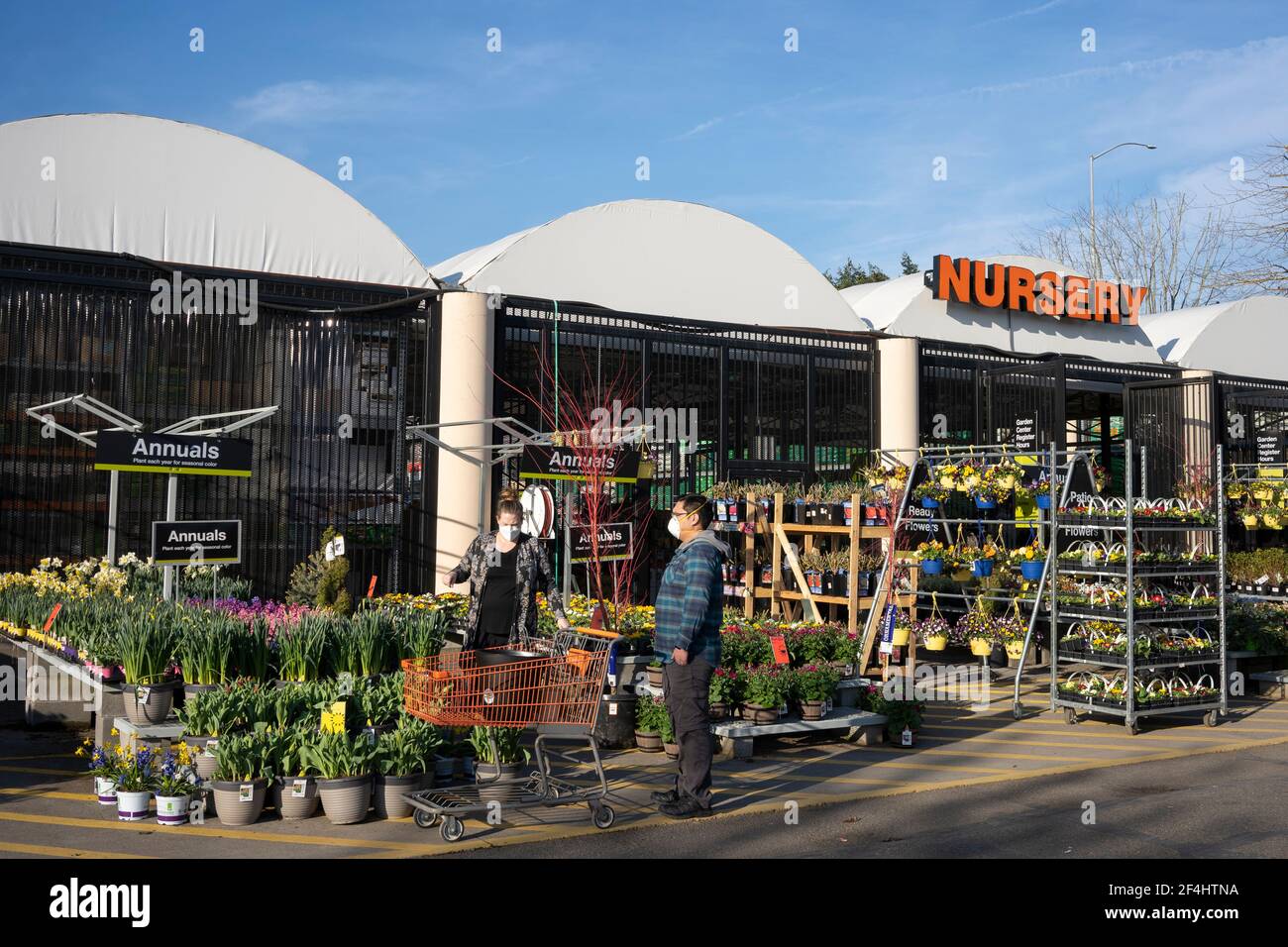 Maskiertes Paar, das am 13. März 2021 in der Gärtnerei im Home Depot in Tigard, Oregon, Pflanzen auswählt, während sich der Frühling inmitten der Pandemie nähert. Stockfoto