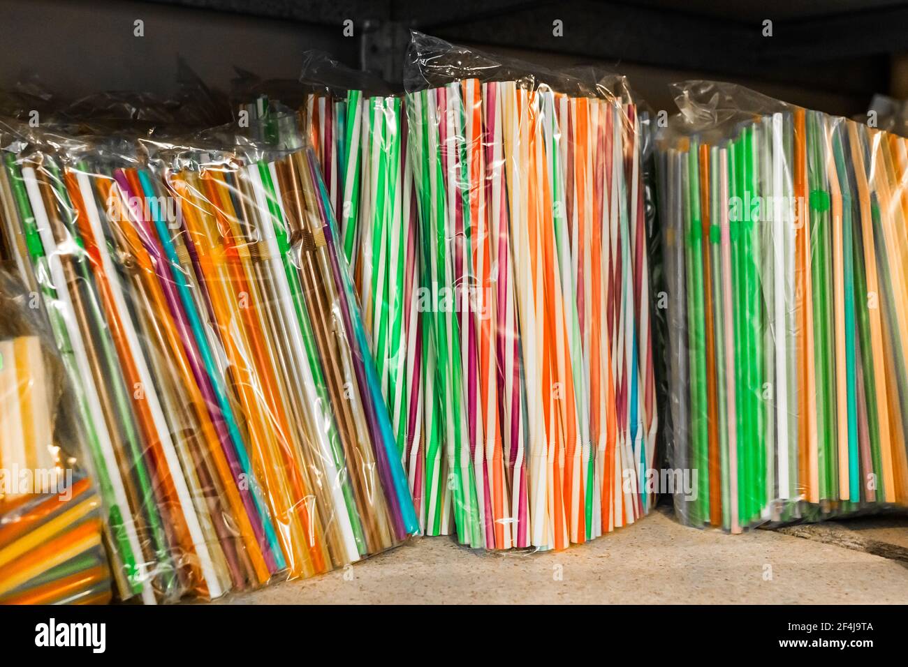 Set von mehrfarbigen Kunststoff-Trinkhalmen auf einem Regal in einem Geschäft aus nächster Nähe. Stockfoto
