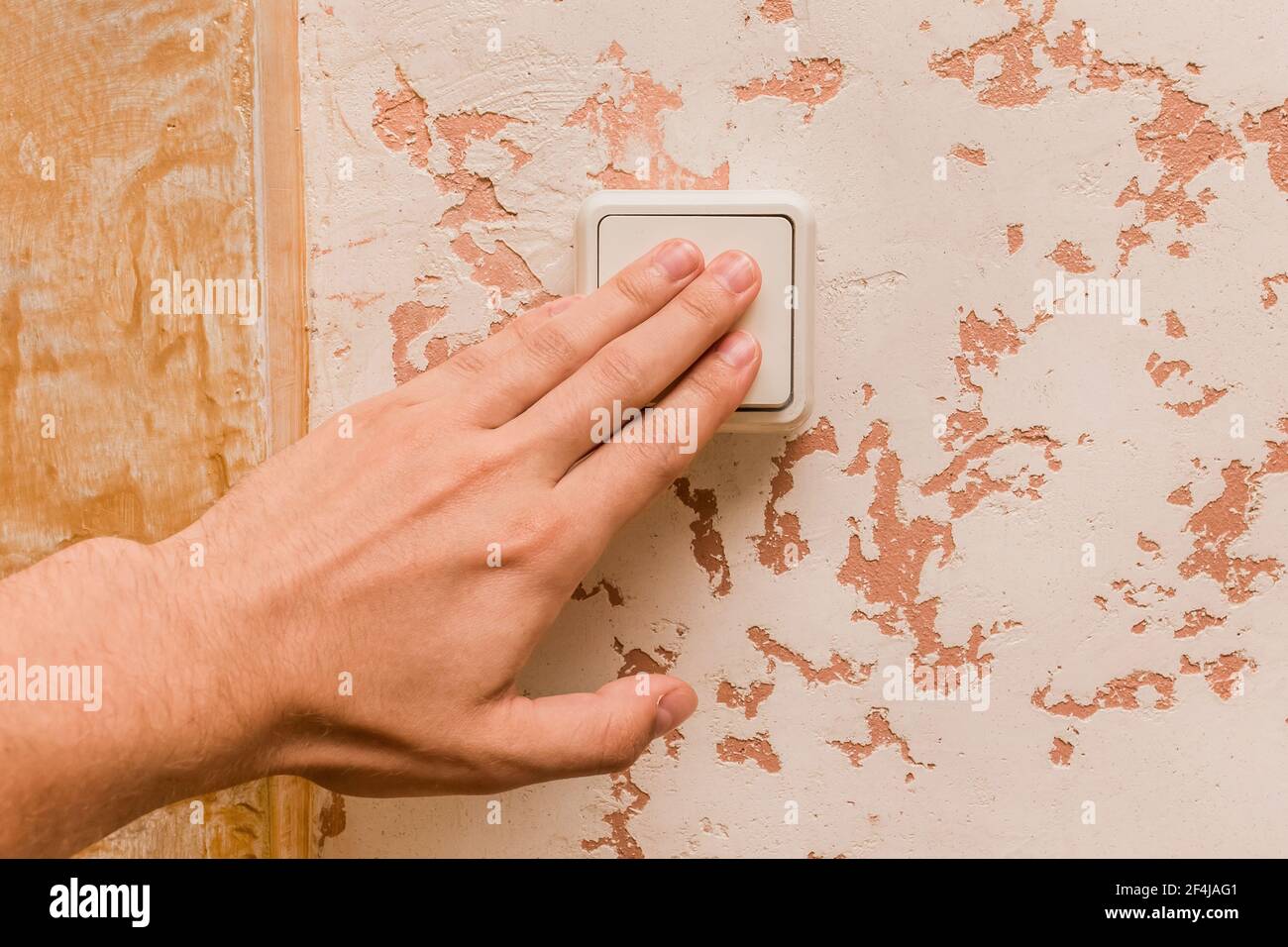 Die Hand des Mannes schaltet das Licht mit einem elektrischen Schalter in einem modernen Raum Innenhintergrund aus. Stockfoto