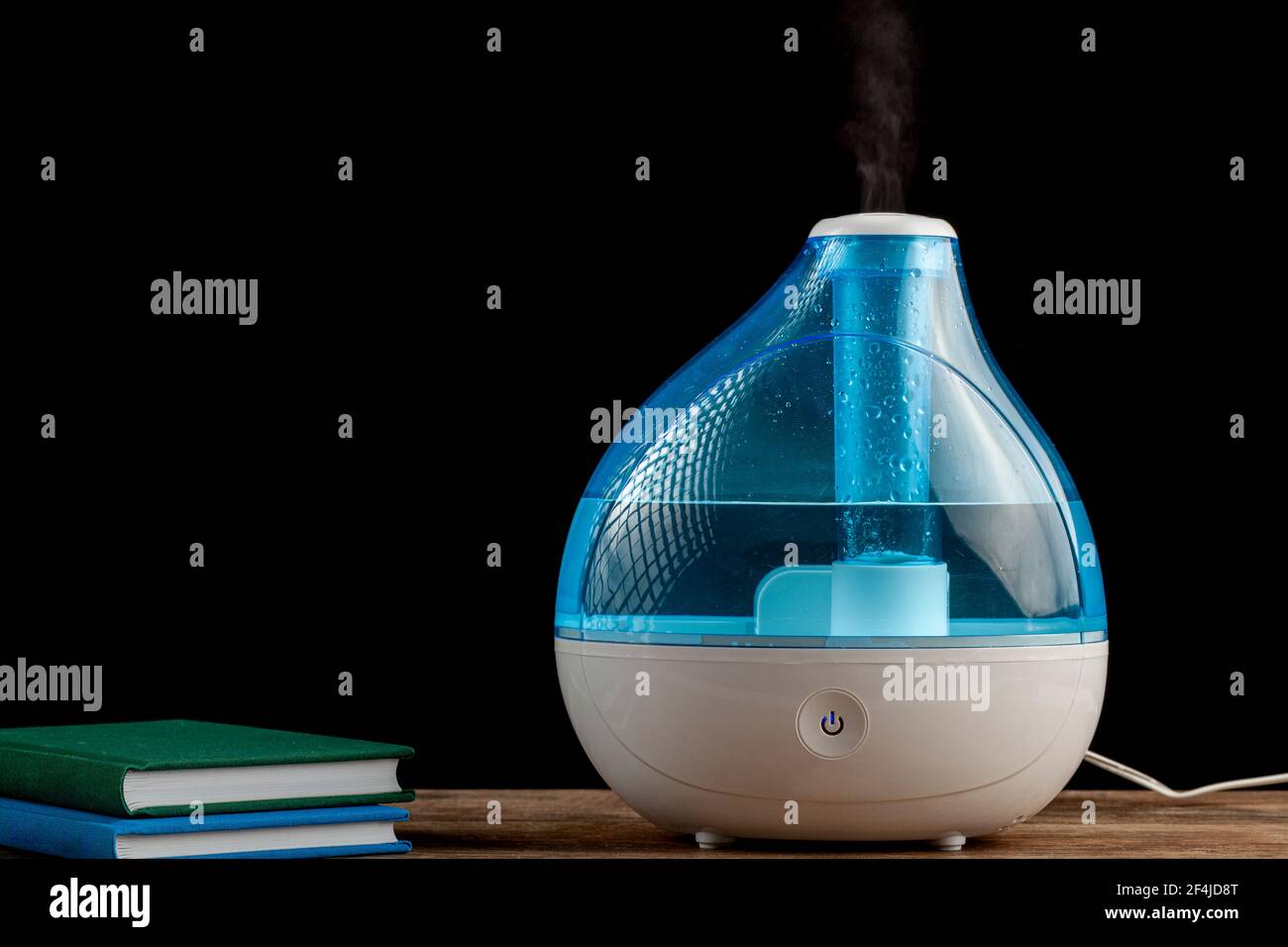 Winternacht, Kälte, Grippe-Konzepte mit einem Ultraschall-Luftbefeuchter erzeugen kühlen Nebel Wasserdampf. Stapel von Büchern sind auch auf hölzernen Tischplatte gesehen. Stockfoto