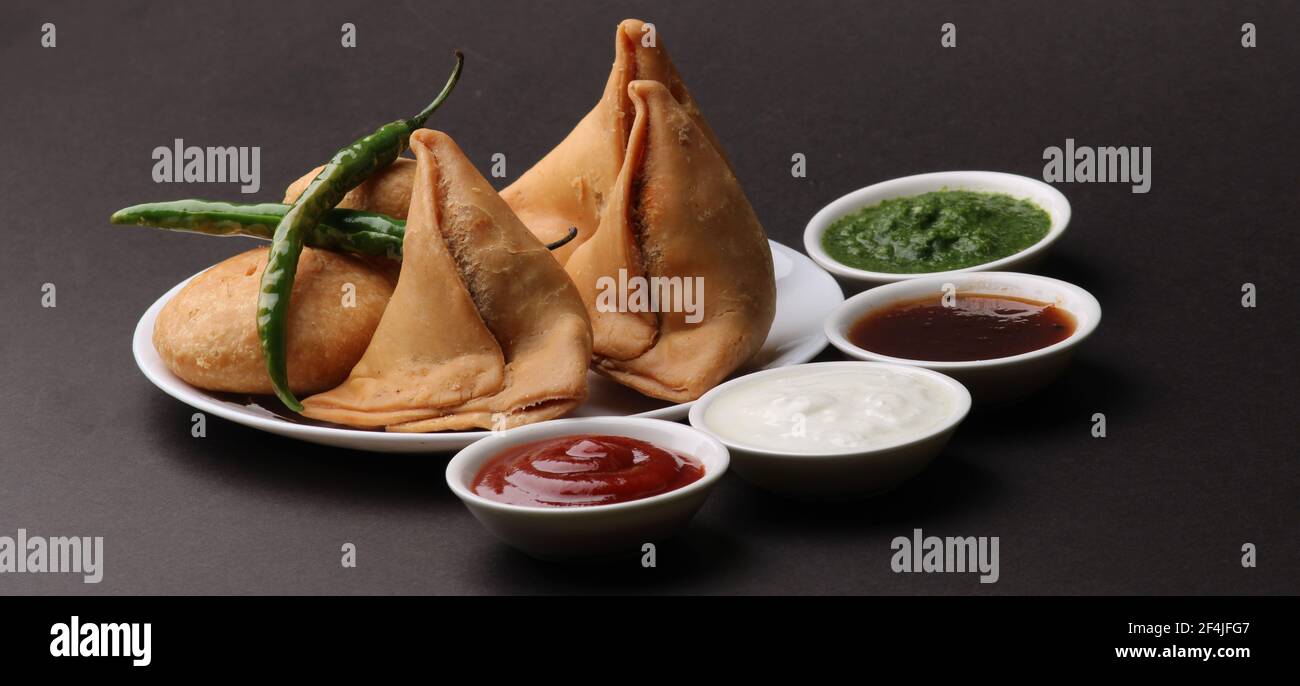 Kachori und Samosa, indische vegetarische Snacks mit grünen und Tamarinden-Chutneys. Stockfoto