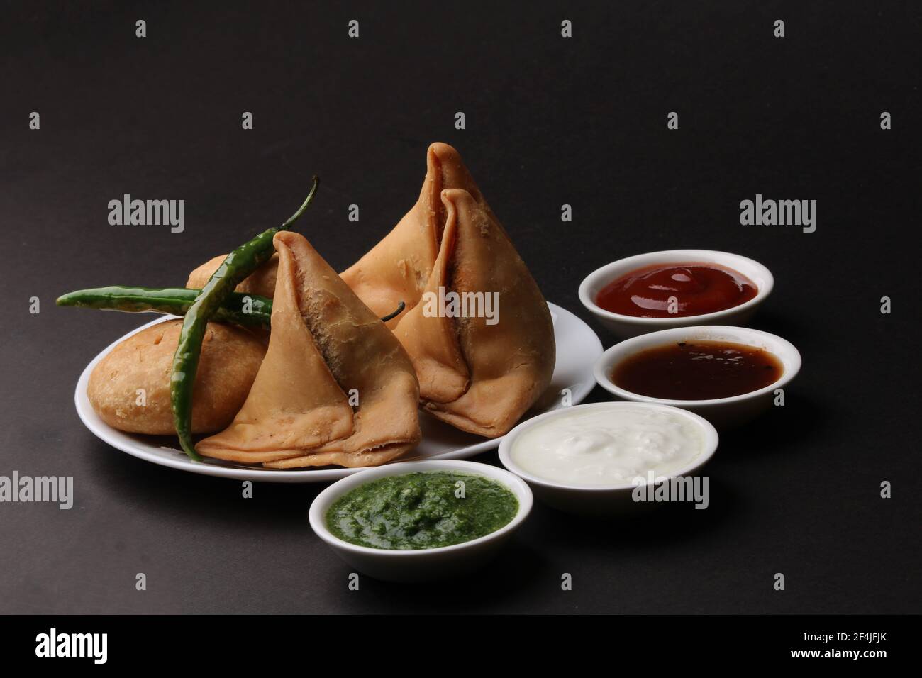 Kachori und Samosa, indische vegetarische Snacks mit grünen und Tamarinden-Chutneys. Stockfoto