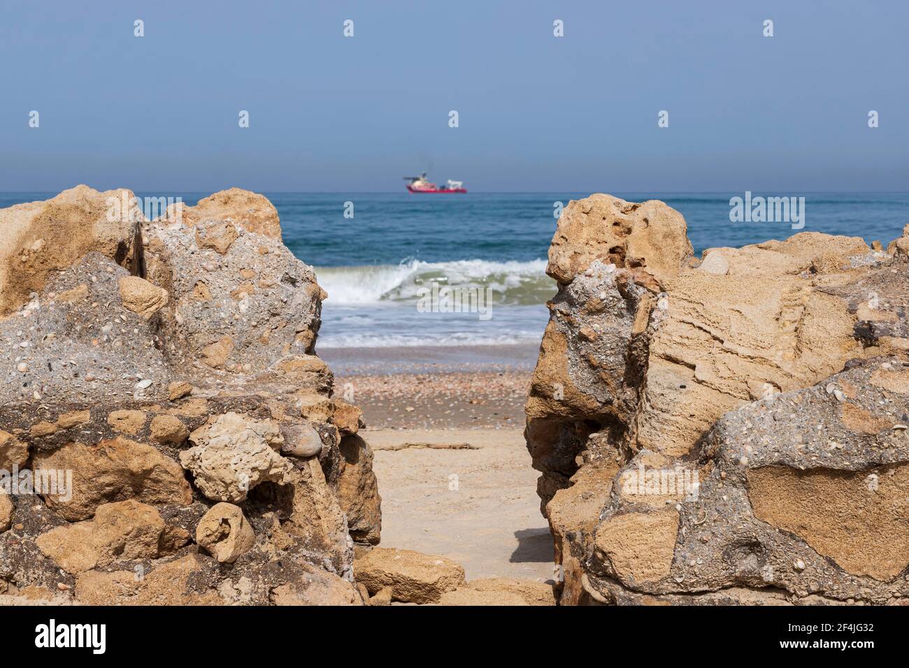 Blick auf das Mittelmeer und das Schiff durch die Muschelsteinformationen am Ufer Stockfoto