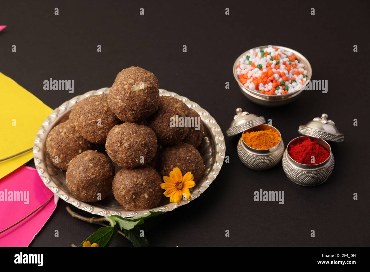 Til Gul ODER Sweet Sesam Laddu mit Drachenmodell, haldi Kumkum und Zuckerkristallen für das Makar Sankranti Festival auf schwarzem Hintergrund. Stockfoto