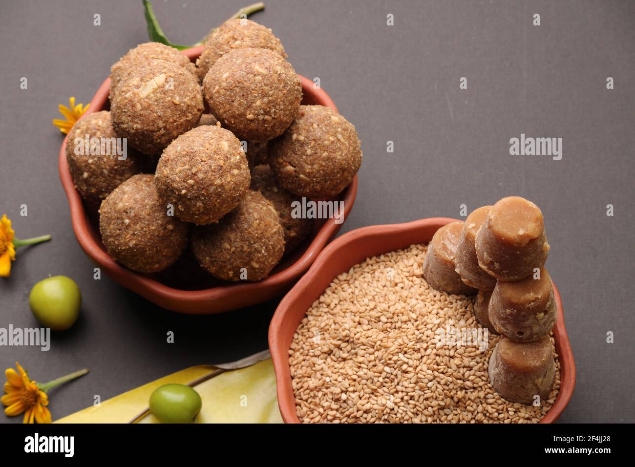 Til Gul ODER Sweet Sesam Laddu mit Drachenmodell, haldi Kumkum und Zuckerkristallen für das Makar Sankranti Festival auf schwarzem Hintergrund. Stockfoto