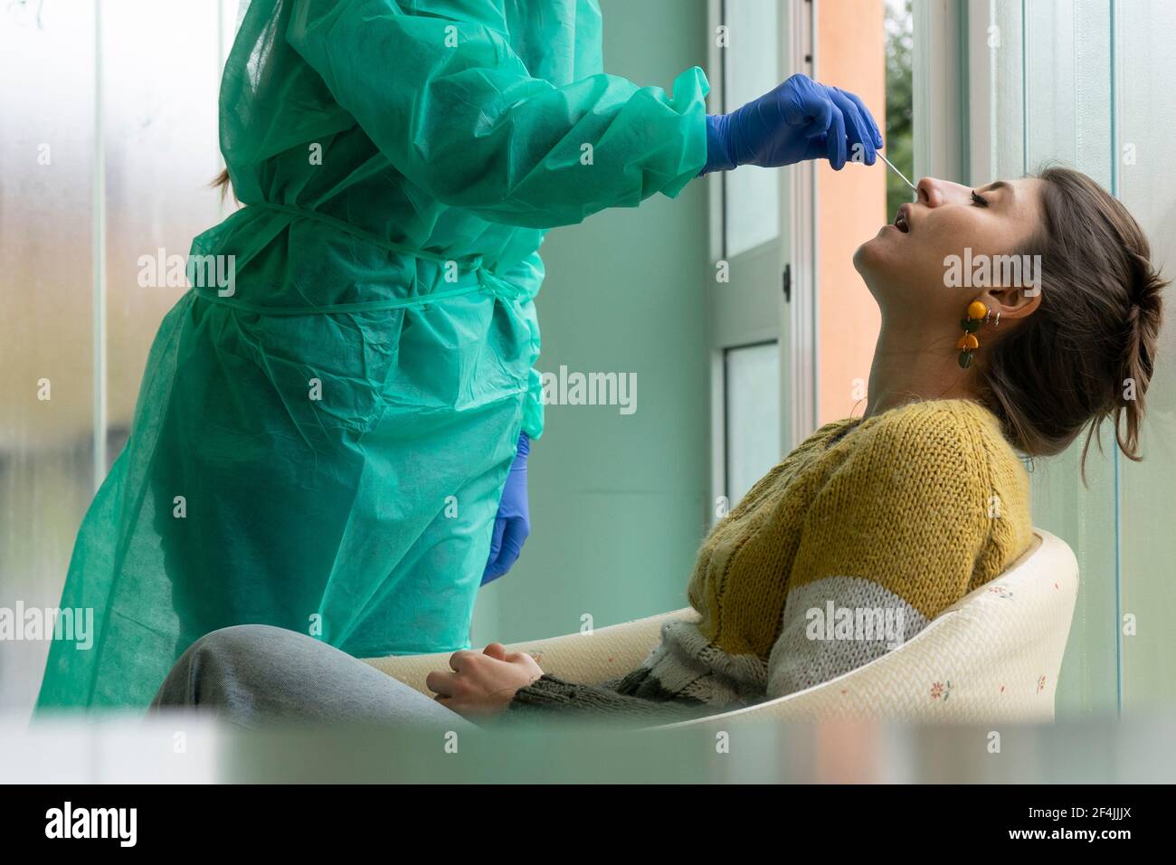 Gesundheitsarbeiter mit Schutzausrüstung führt Coronavirus Abstrichbesteck auf kaukasischen Mädchen.Nasenabstrich für Covid-19. Stockfoto