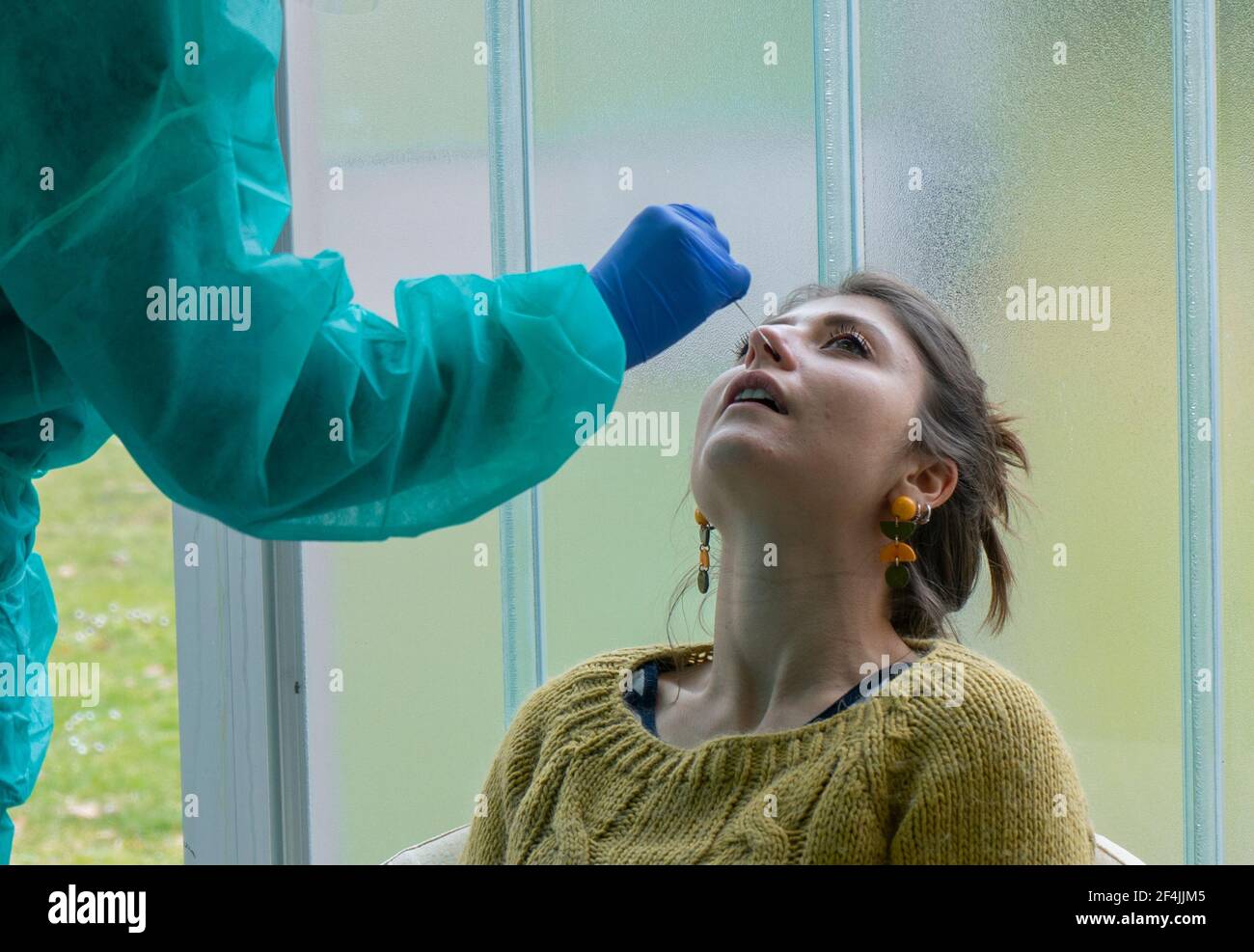 Gesundheitsarbeiter mit Schutzausrüstung führt Coronavirus Abstrichbesteck auf kaukasischen Mädchen.Nasenabstrich für Covid-19. Stockfoto