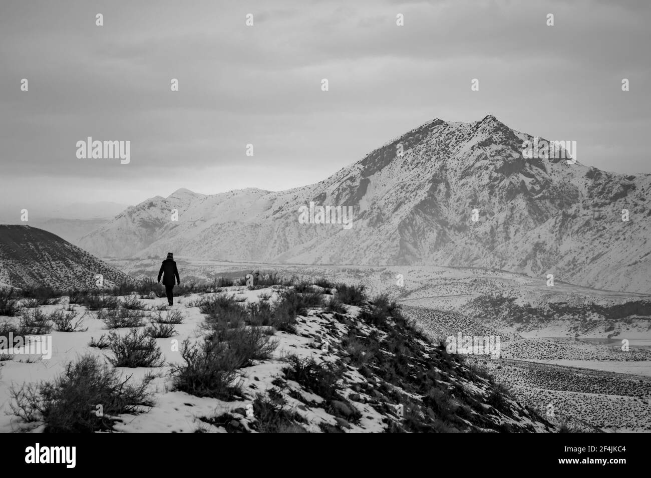 Schwarz-Weiß-Foto einer unbekannten Person, die am Ufer des Azat-Stausees in Armenien entlang wandert, mit dem Berg Yeranos im Hintergrund Stockfoto