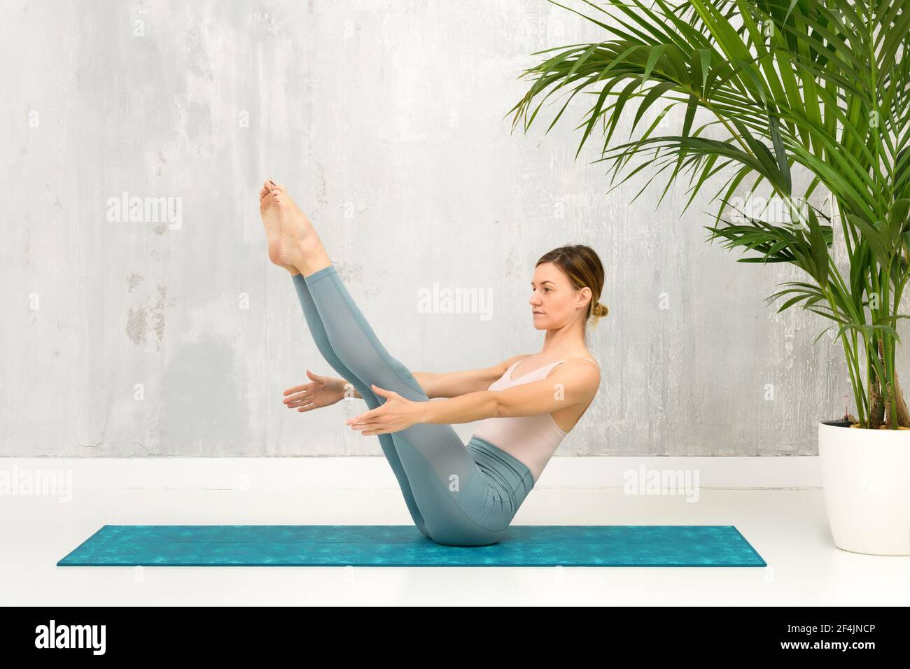 Fit gesunde Frau tun eine Navasana Yoga Pose oder Boot Pose zur Stärkung und Dehnung der Wirbelsäule, Bauchmuskeln und Hüftbeuger Muskeln auf einer Matte vor Stockfoto